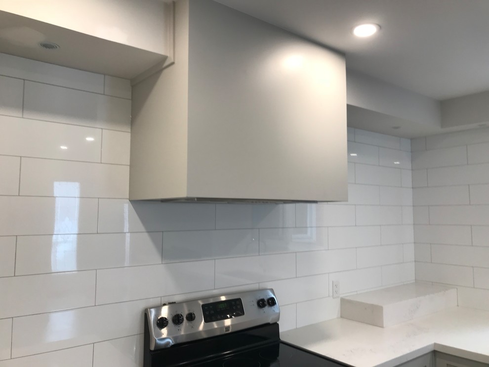 Home design - mid-sized transitional porcelain tile and brown floor home design idea in Toronto with an undermount sink, shaker cabinets, gray cabinets, quartz countertops, white backsplash, subway tile backsplash, stainless steel appliances, an island and white countertops