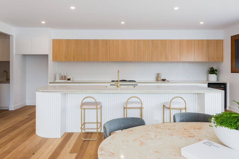 Ejemplo de cocina actual grande con salpicadero blanco, electrodomésticos de acero inoxidable, suelo de madera en tonos medios y península