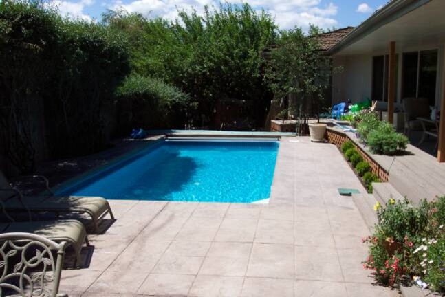 Mid-sized traditional backyard rectangular pool in Other with tile.