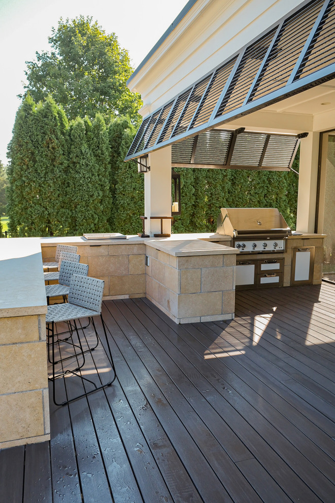 Large beach style backyard and ground level deck in Minneapolis with an outdoor kitchen, a roof extension and mixed railing.