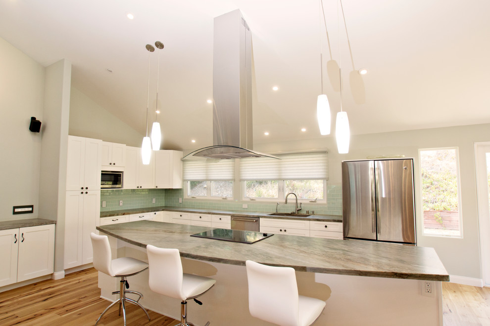 Inspiration for a mid-sized transitional l-shaped eat-in kitchen in San Diego with a drop-in sink, shaker cabinets, white cabinets, quartz benchtops, green splashback, glass tile splashback, stainless steel appliances, light hardwood floors, with island, brown floor and green benchtop.
