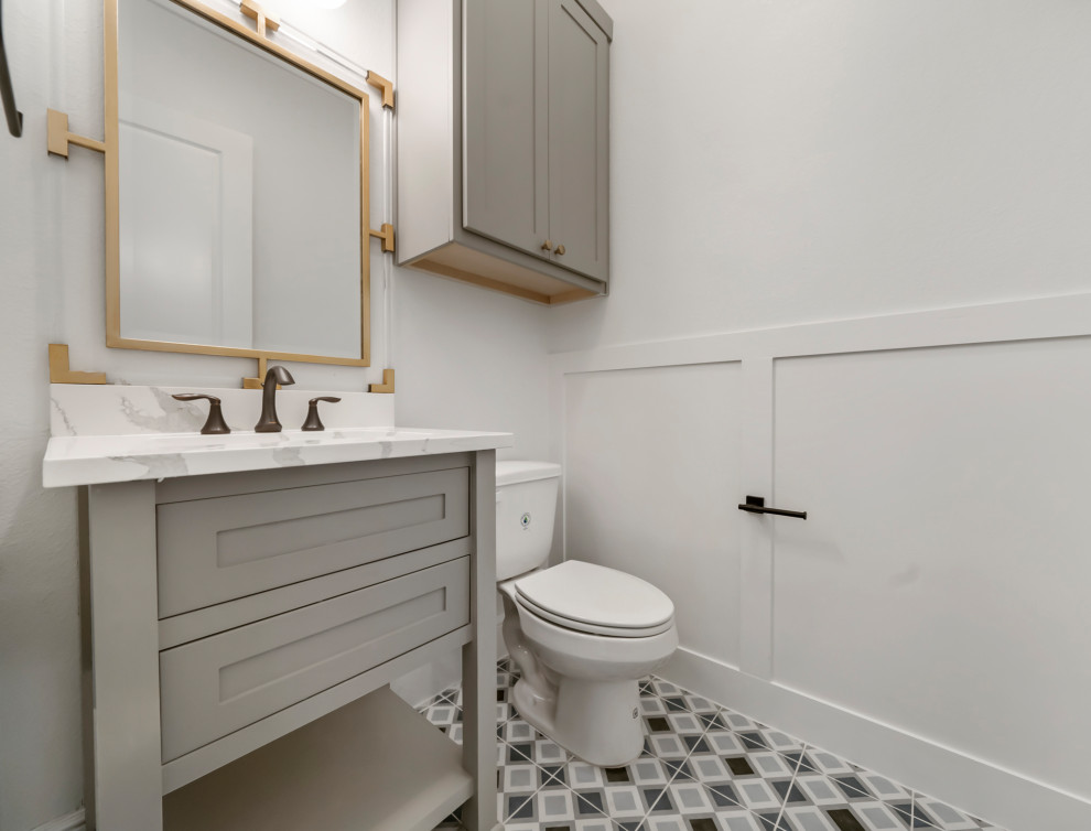Aménagement d'un WC et toilettes classique avec des portes de placard grises, un mur gris, un sol en carrelage de céramique, un plan de toilette en marbre, un sol gris, un plan de toilette blanc, meuble-lavabo sur pied et du lambris.