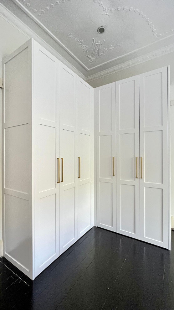 Exemple d'une grande armoire encastrée neutre avec un placard à porte shaker, des portes de placard blanches, parquet foncé et un sol noir.