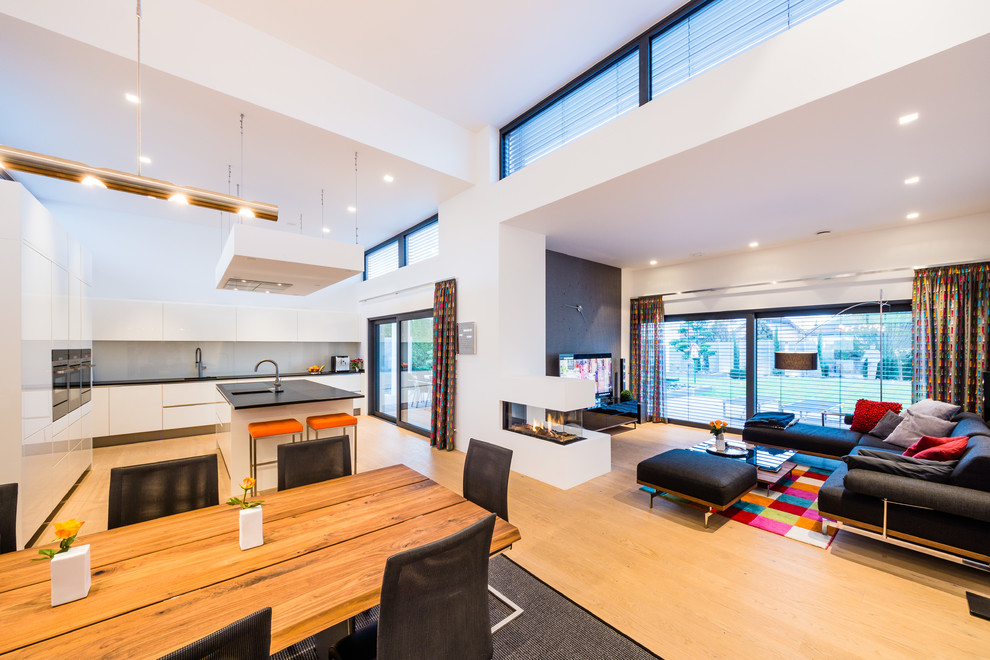 Großes, Offenes Modernes Wohnzimmer mit weißer Wandfarbe, braunem Holzboden, Kamin, verputzter Kaminumrandung und freistehendem TV in Frankfurt am Main