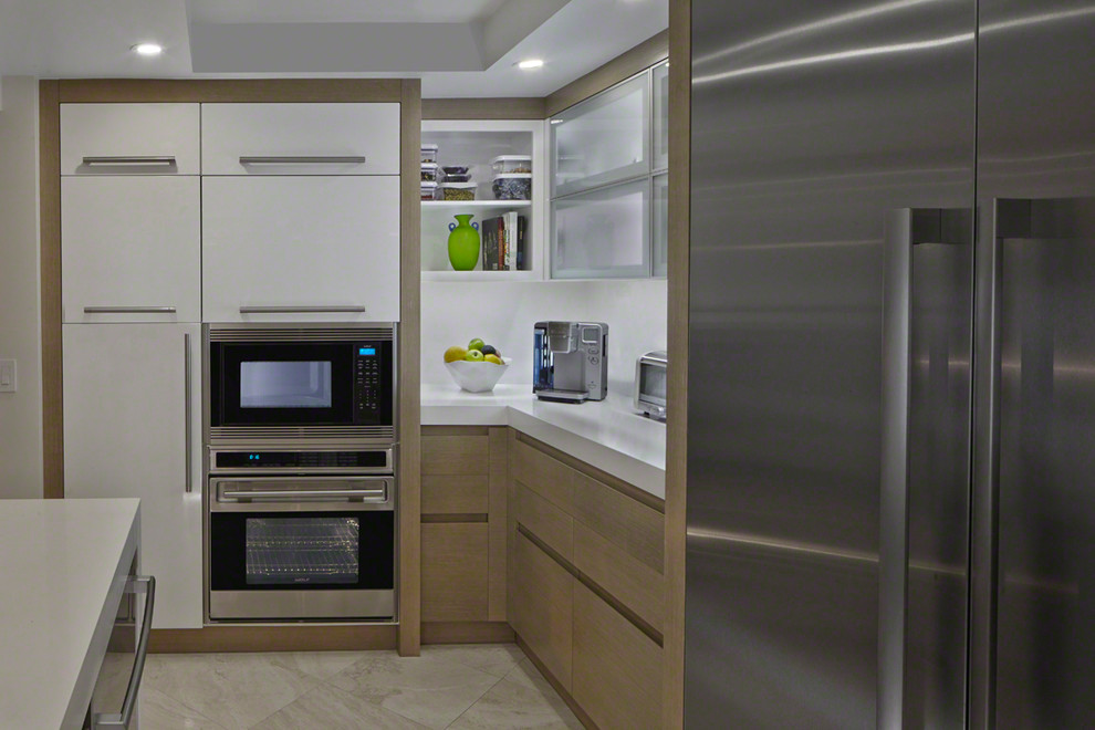 Photo of a mid-sized modern u-shaped kitchen in Miami with an undermount sink, flat-panel cabinets, light wood cabinets, solid surface benchtops, stainless steel appliances, porcelain floors, no island and beige floor.