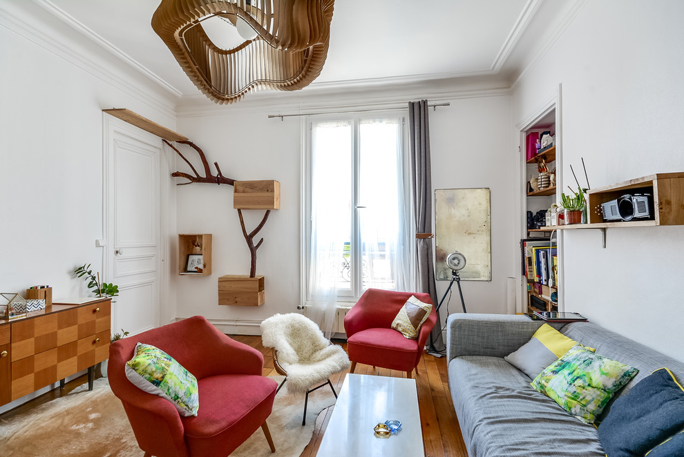 Photo of an eclectic living room in Paris with white walls and medium hardwood floors.