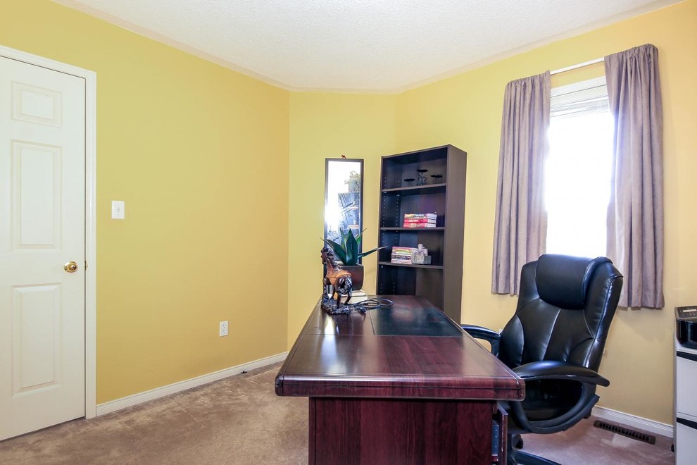 Inspiration for a mid-sized transitional home studio in Toronto with yellow walls, carpet, no fireplace and a freestanding desk.