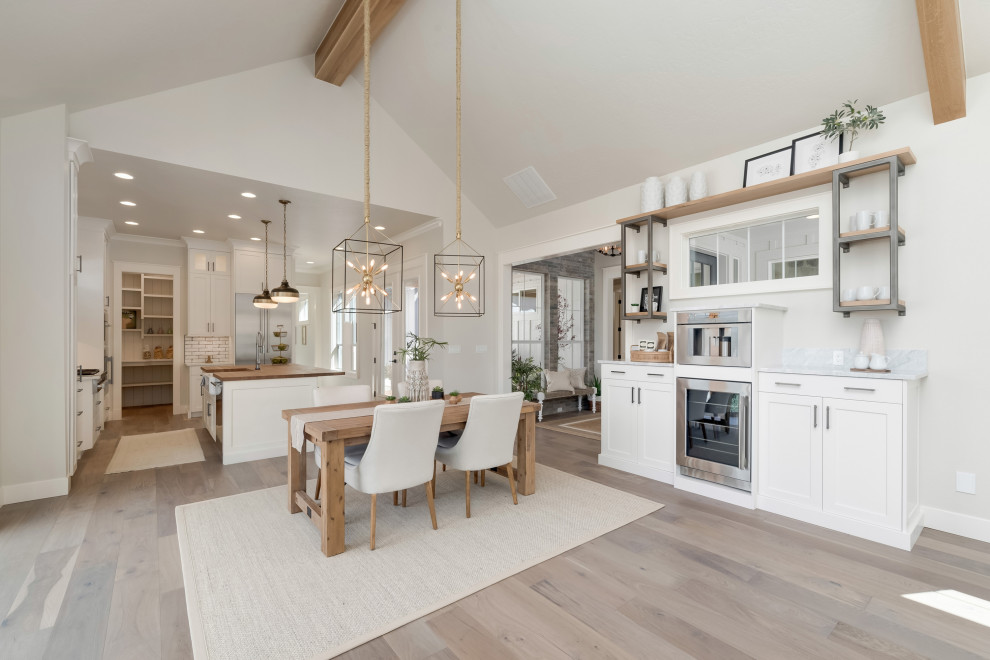 This is an example of a mid-sized country kitchen/dining combo in Boise with grey walls, light hardwood floors, a standard fireplace, a stone fireplace surround and grey floor.