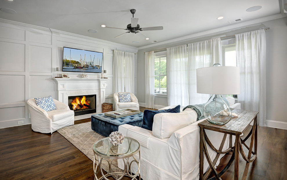 This is an example of a beach style family room in Charleston with grey walls, dark hardwood floors, a standard fireplace and a wall-mounted tv.