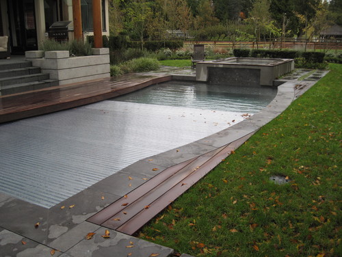 A Ridged automatic cover on this pool. The automatic cover here lays under the lip of the pool, and is made from a ridged material. The harder material adds to the durability of the cover. 