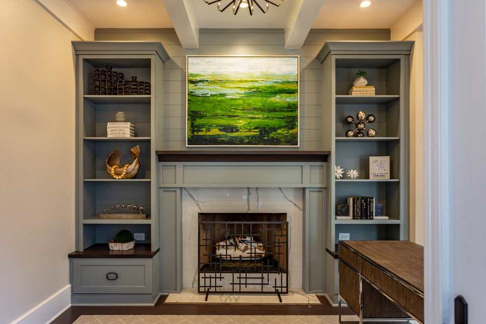 Photo of a mid-sized transitional study room in Charlotte with grey walls, medium hardwood floors, a standard fireplace, a stone fireplace surround, a freestanding desk and brown floor.