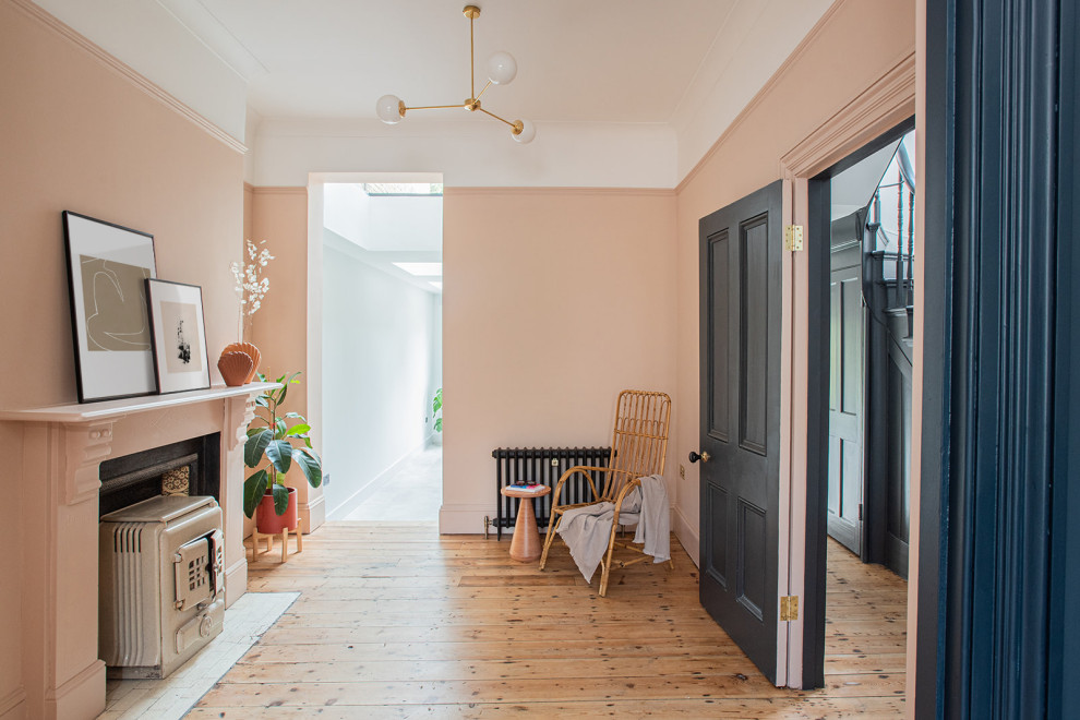 Ispirazione per un soggiorno minimal con pareti rosa, pavimento in legno massello medio, camino classico e cornice del camino piastrellata
