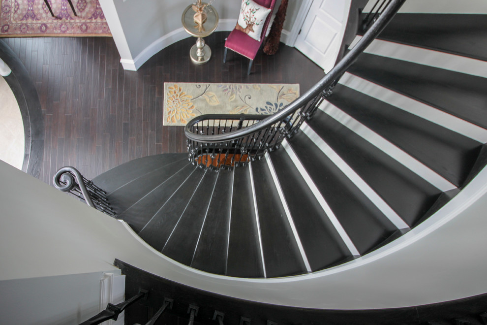Expansive transitional wood curved staircase in DC Metro with wood risers and mixed railing.