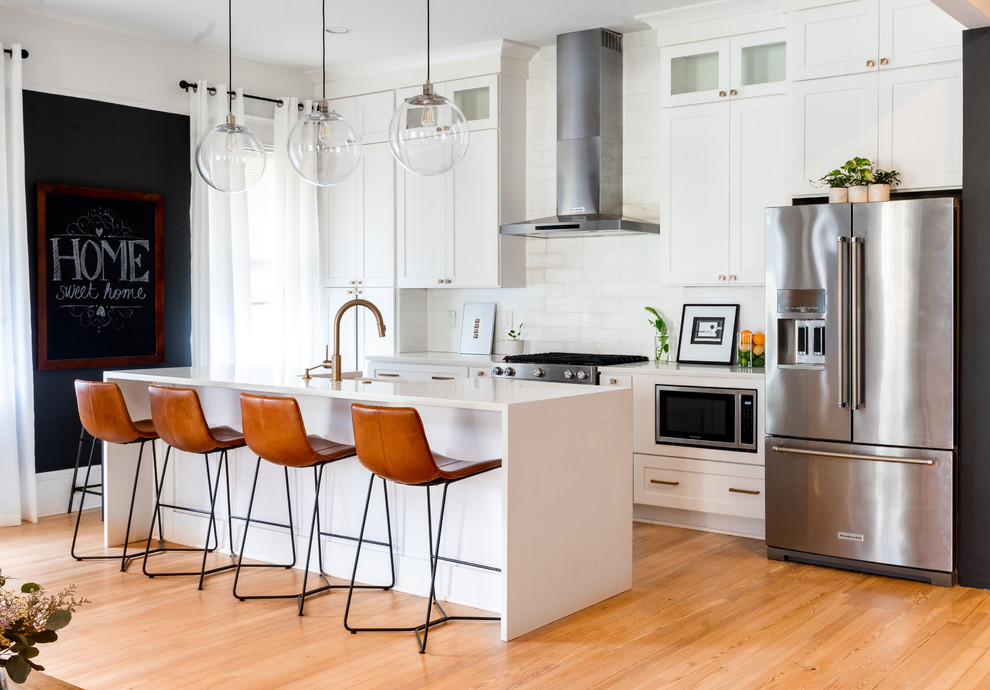 Inspiration for a large contemporary single-wall open plan kitchen in Atlanta with shaker cabinets, white cabinets, white splashback, with island, brown floor, white benchtop, quartz benchtops, stainless steel appliances and light hardwood floors.