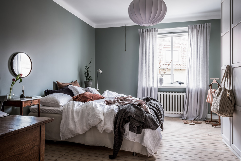 Large scandinavian master bedroom in Gothenburg with grey walls, light hardwood floors, no fireplace and beige floor.