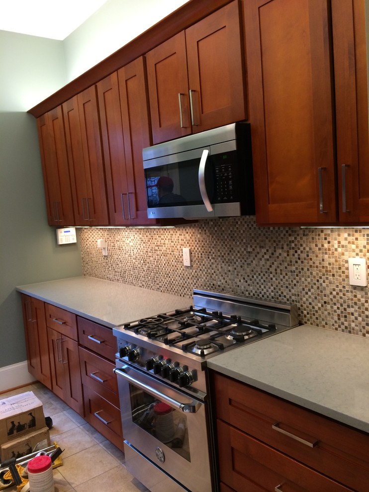 Inspiration for a mid-sized transitional u-shaped limestone floor and beige floor kitchen remodel in Orange County with an undermount sink, shaker cabinets, medium tone wood cabinets, quartz countertops, beige backsplash, mosaic tile backsplash, stainless steel appliances and an island
