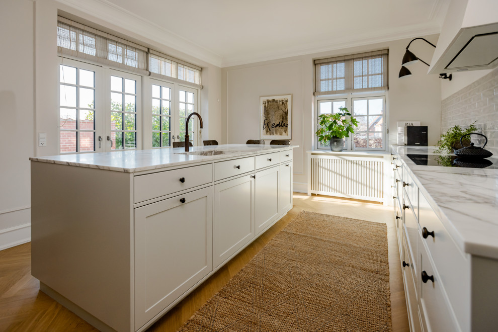 Photo of a farmhouse kitchen in Odense with a single-bowl sink, shaker cabinets, marble worktops, an island and multicoloured worktops.
