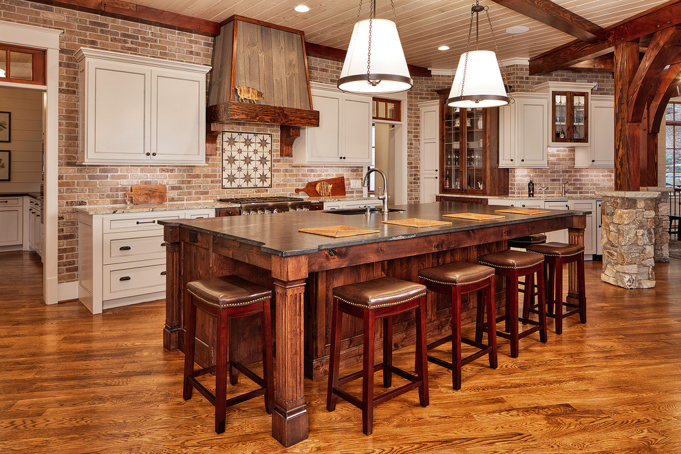 Photo of a country kitchen in Other with an undermount sink, recessed-panel cabinets, beige cabinets, brick splashback, stainless steel appliances, medium hardwood floors, with island and beige benchtop.