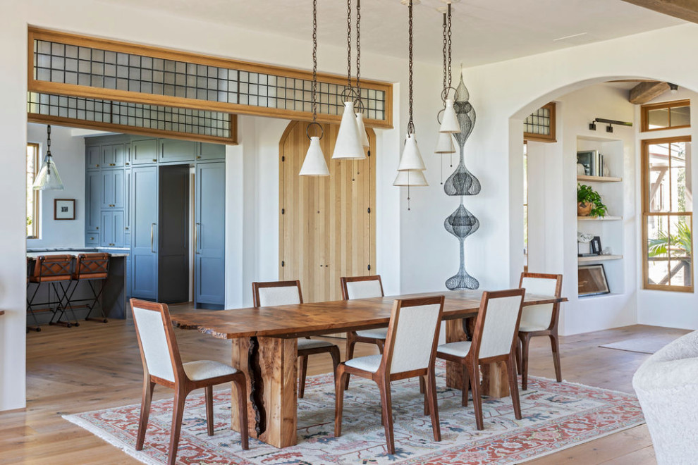 Ispirazione per un'ampia sala da pranzo aperta verso il soggiorno mediterranea con pareti bianche, parquet chiaro, pavimento marrone e travi a vista