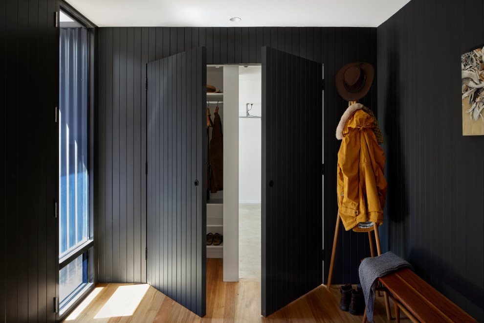 Modernes Foyer mit schwarzer Wandfarbe, hellem Holzboden, beigem Boden und Holzdielenwänden in Melbourne