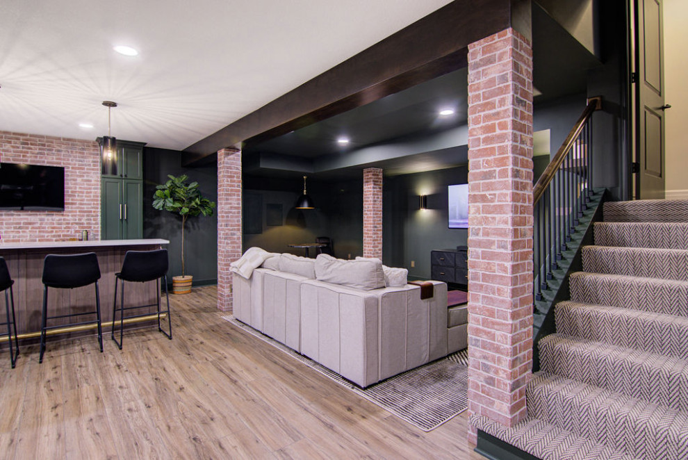Large modern walk-out basement in Kansas City with a home bar, green walls, vinyl floors, exposed beam and brick walls.
