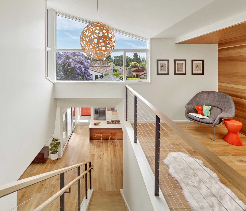 Photo of a midcentury loft-style family room in San Francisco with white walls, light hardwood floors and beige floor.