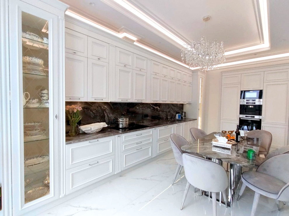 This is an example of a large transitional single-wall eat-in kitchen in Moscow with a double-bowl sink, recessed-panel cabinets, white cabinets, quartz benchtops, black splashback, engineered quartz splashback, stainless steel appliances, porcelain floors, white floor, black benchtop and recessed.