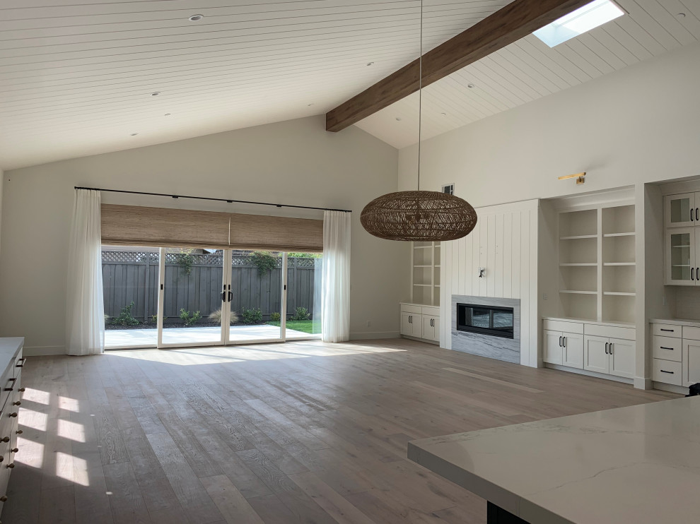 Photo of a large country open plan games room in San Francisco with a home bar, white walls, a ribbon fireplace, a stone fireplace surround, a wall mounted tv, grey floors, a vaulted ceiling and tongue and groove walls.