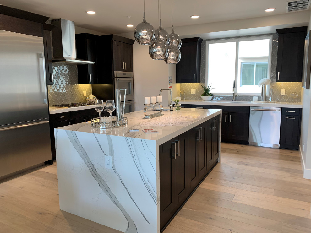 Inspiration for a mid-sized transitional u-shaped medium tone wood floor and beige floor eat-in kitchen remodel in Phoenix with an undermount sink, shaker cabinets, dark wood cabinets, quartz countertops, gray backsplash, glass tile backsplash, stainless steel appliances, an island and white countertops