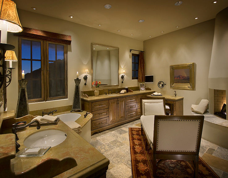 This is an example of a large mediterranean master bathroom in Phoenix with recessed-panel cabinets, medium wood cabinets, granite benchtops, gray tile, a corner tub, an undermount sink, beige walls and slate floors.