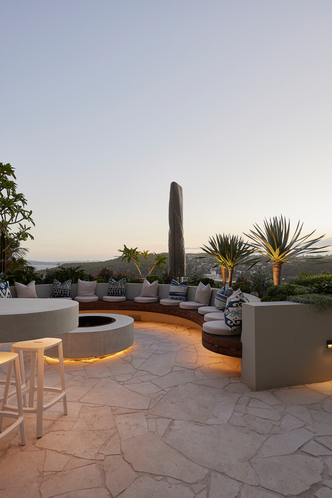 Inspiration for a contemporary patio in Sydney with a fire feature, natural stone pavers and no cover.