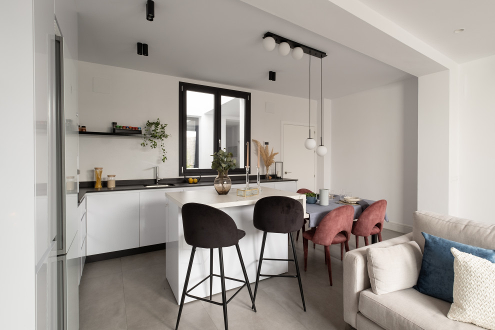 Design ideas for an expansive modern grey and white l-shaped open plan kitchen in Seville with a built-in sink, flat-panel cabinets, white cabinets, grey splashback, porcelain splashback, white appliances, porcelain flooring, an island, grey floors and white worktops.