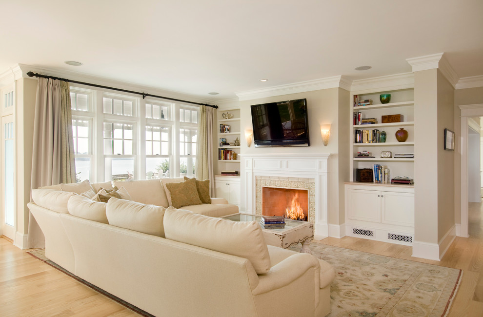 Family room - large traditional open concept light wood floor family room idea in Boston with beige walls, a standard fireplace, a wall-mounted tv and a tile fireplace