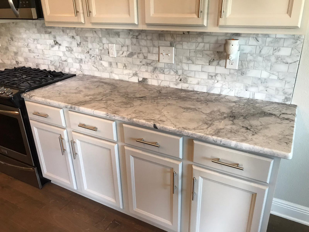 Example of a large kitchen design with a double-bowl sink, white cabinets, quartzite countertops, multicolored backsplash, stone tile backsplash, stainless steel appliances, an island and multicolored countertops