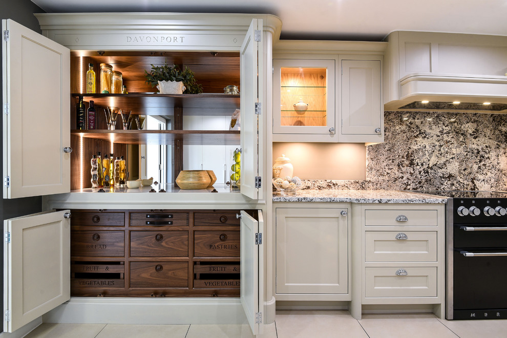 Traditional kitchen pantry in Berkshire with recessed-panel cabinets, beige cabinets, stone slab splashback, black appliances, beige floor and grey benchtop.