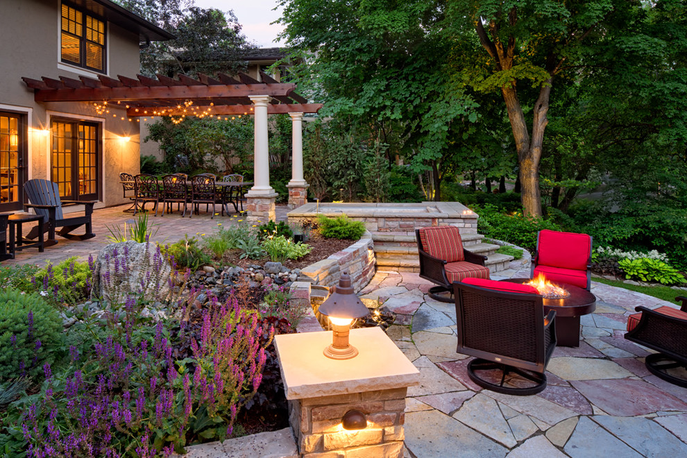 Photo of a large transitional backyard patio in Minneapolis with a water feature, natural stone pavers and a pergola.