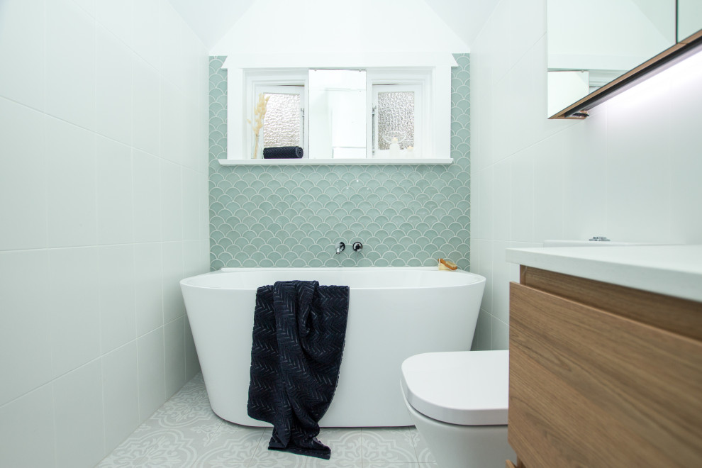 Inspiration for a small modern ensuite bathroom in Sydney with medium wood cabinets, a freestanding bath, a corner shower, a two-piece toilet, white tiles, a vessel sink, a hinged door, white worktops, a wall niche, a single sink and a floating vanity unit.