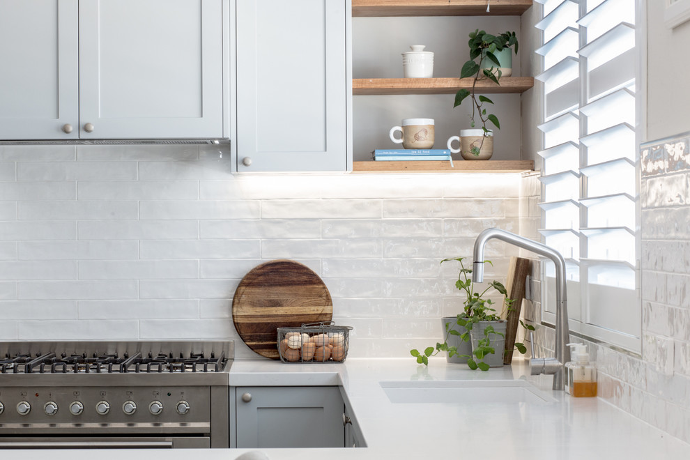 Inspiration for a mid-sized contemporary u-shaped eat-in kitchen in Brisbane with an undermount sink, recessed-panel cabinets, grey cabinets, quartz benchtops, white splashback, subway tile splashback, stainless steel appliances, porcelain floors, a peninsula, grey floor and white benchtop.