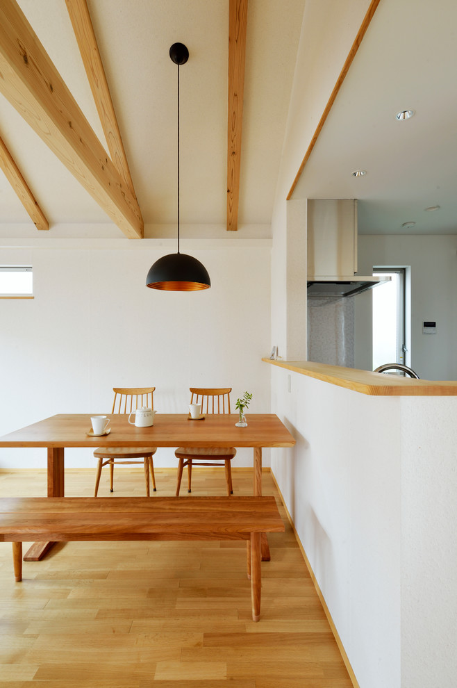 This is an example of an asian kitchen/dining combo in Tokyo with white walls and brown floor.