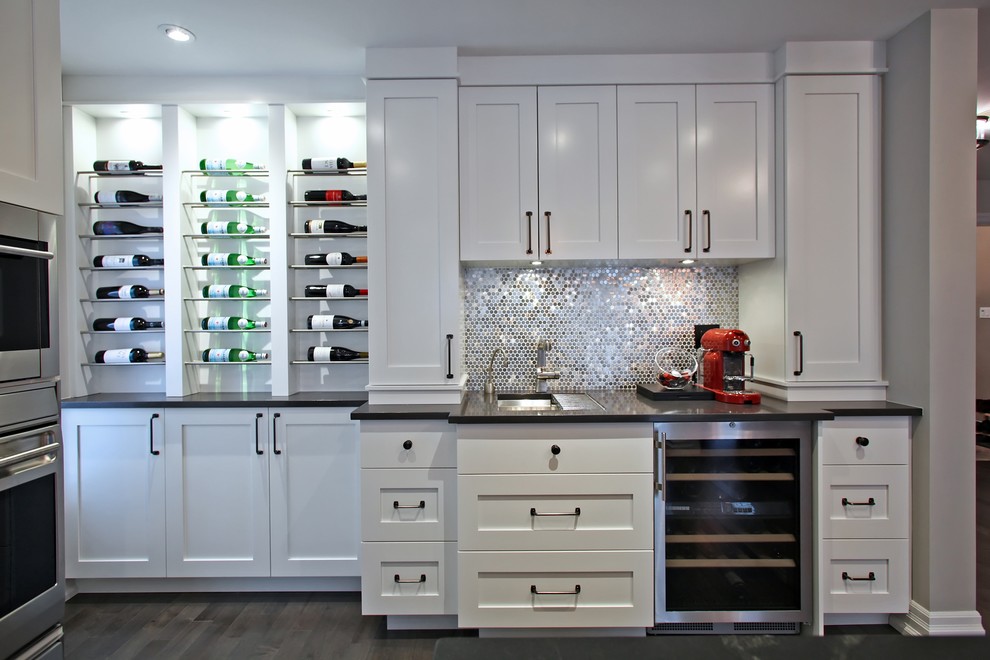 Transitional kitchen in Toronto with soapstone benchtops, stainless steel appliances, an undermount sink, shaker cabinets, white cabinets, metallic splashback and dark hardwood floors.