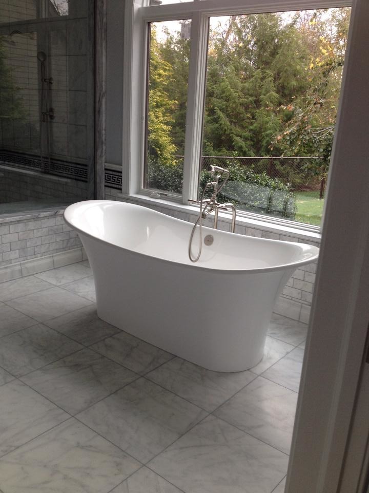 Large gray tile marble floor freestanding bathtub photo with gray cabinets and gray walls