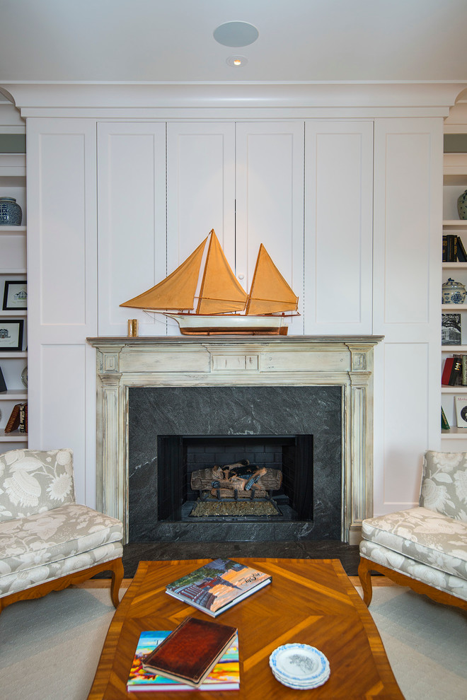 Inspiration for a mid-sized transitional enclosed family room in Charleston with a library, grey walls, medium hardwood floors, a standard fireplace, a stone fireplace surround and a concealed tv.