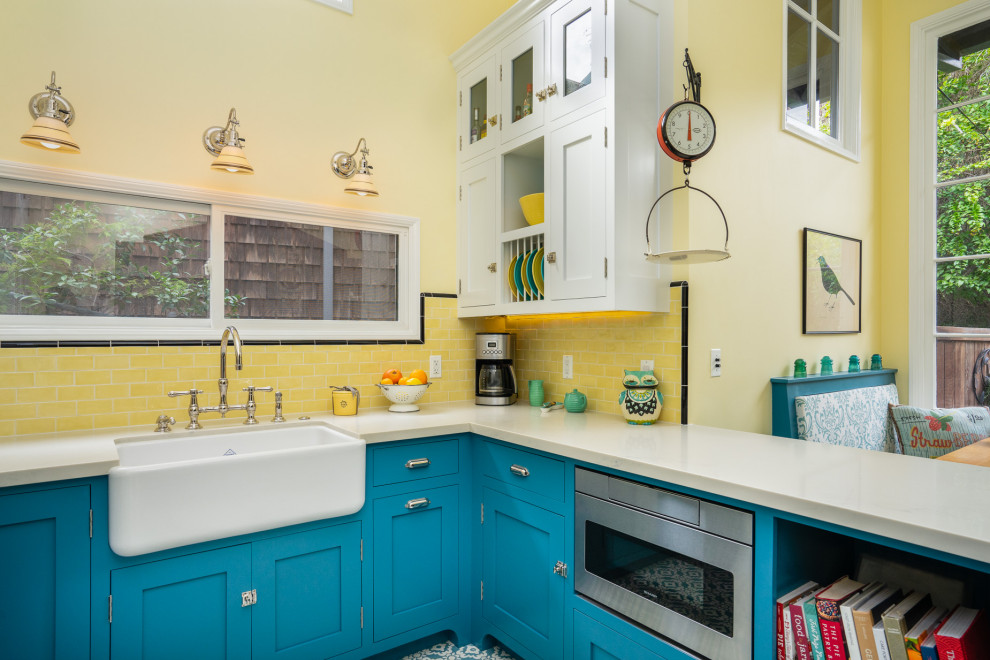Small country u-shaped eat-in kitchen in Los Angeles with a farmhouse sink, beaded inset cabinets, blue cabinets, quartz benchtops, yellow splashback, subway tile splashback, white appliances, cement tiles, blue floor and white benchtop.