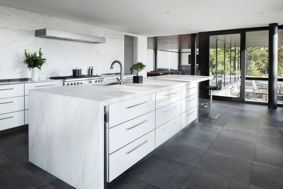 Photo of a large contemporary l-shaped eat-in kitchen in New York with flat-panel cabinets, light wood cabinets, marble benchtops, white splashback, marble splashback, panelled appliances, porcelain floors, with island and white benchtop.