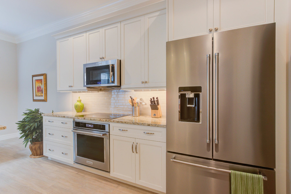 Inspiration for a mid-sized transitional galley porcelain tile and beige floor enclosed kitchen remodel in Miami with a double-bowl sink, flat-panel cabinets, white cabinets, granite countertops, white backsplash, ceramic backsplash and stainless steel appliances
