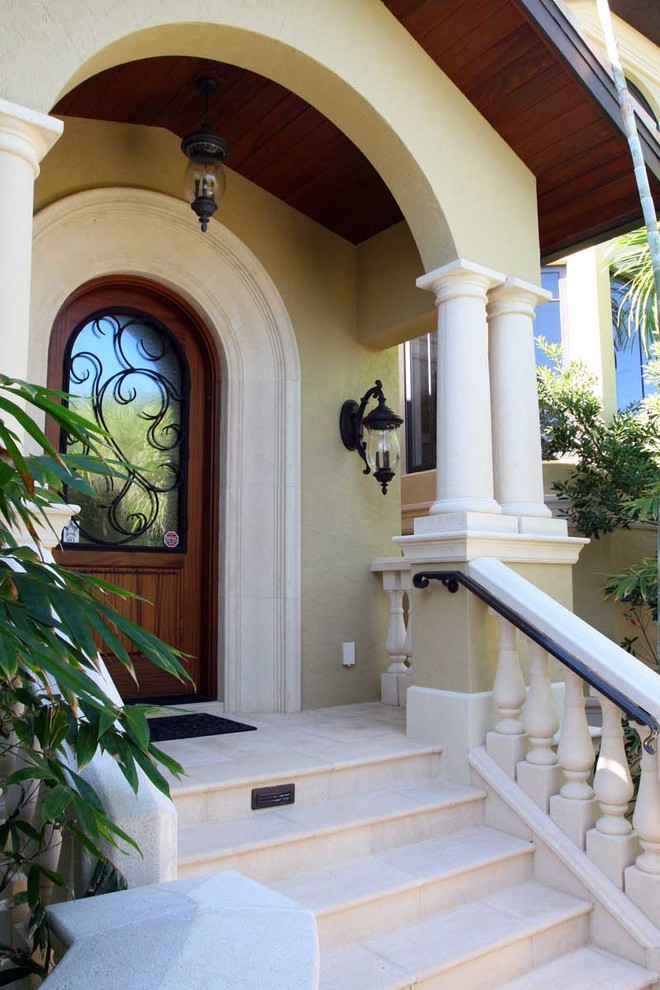 This is an example of a large mediterranean three-storey stucco beige house exterior in Other with a hip roof and a tile roof.