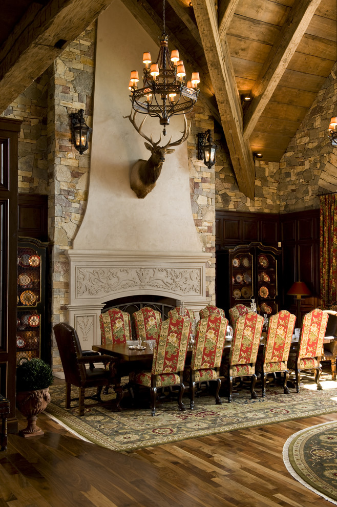 This is an example of a country dining room in Minneapolis with dark hardwood floors and a standard fireplace.