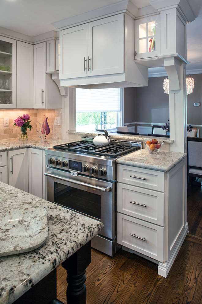 Eat-in kitchen - large transitional galley dark wood floor eat-in kitchen idea with an undermount sink, shaker cabinets, white cabinets, granite countertops, beige backsplash, stone tile backsplash, stainless steel appliances, brown walls and an island