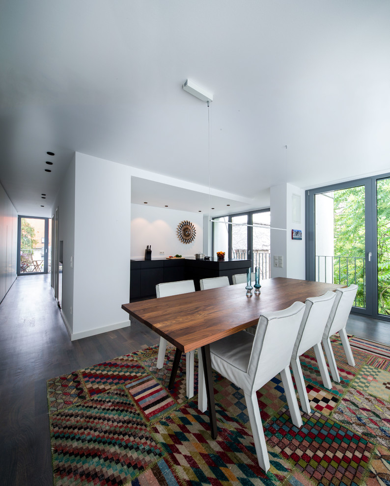 This is an example of a large contemporary kitchen/dining combo in Frankfurt with white walls and dark hardwood floors.