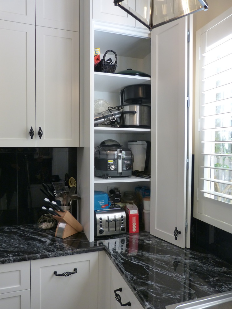 Mid-sized traditional u-shaped separate kitchen in Adelaide with a double-bowl sink, shaker cabinets, white cabinets, granite benchtops, black splashback, glass tile splashback, white appliances, slate floors, with island, black floor and black benchtop.